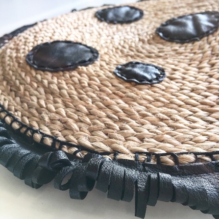 round leather decorations attached to a straw bag